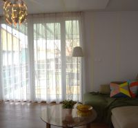Living room in a family house with a sofa, wooden decor flooring, and a glass wall.