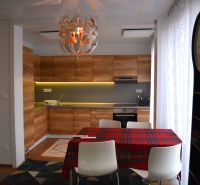 A kitchen with a wood-patterned floor, a table, and decorative lighting in a family house.
