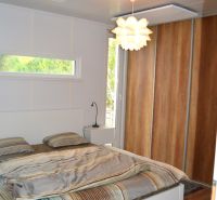 Bedroom in a family house with a bed, light fixture, and built-in wardrobe.