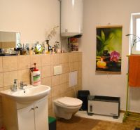 Bathroom with a sink, wall-mounted toilet, water heater, and decorative curtain.