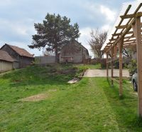 The courtyard of a family house in Nižná with a car, a shelter, and greenery.