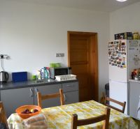 A kitchen in a family house with a dining table, refrigerator, and kitchen unit.