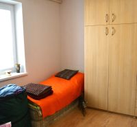 A room in a family house with a bed, a wardrobe, and a floor with a wooden decor.