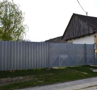 A family house in Nižná with a metal fence and gate, standing next to a tree.