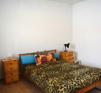 Bedroom in a family house with a bed, nightstands, and a wooden decor floor.