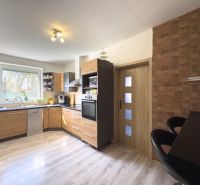 A kitchen in a family house with a wooden decor floor and brick cladding.