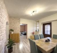 A dining room in a family house with a wooden decor floor and a stone wall.