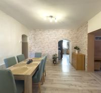 The dining room of a family house with a wooden decor floor and brick wallpaper.