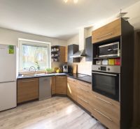 A kitchen in a family house with a wooden decor floor and modern equipment.