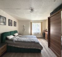 A bedroom in a family house with a large bed and a floor with a wooden decor.