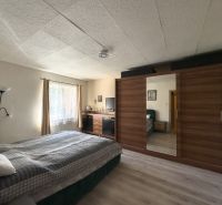 A bedroom in a family house with a bed, a wardrobe, and a floor with a wooden decor.