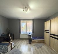 Bedroom with a large wardrobe, a desk, and a wooden decor floor in a family house.