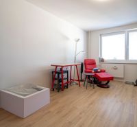 A room in a 2-room apartment with an armchair, a table, and a floor with a wooden decor.