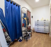 Entrance hall with a coat rack, blue curtain, and wood-patterned flooring in a 2-room apartment.