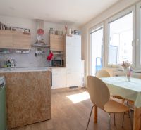 A kitchen in a 2-room apartment with a table and a wooden decor floor.