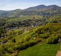 A landscape view of family houses in Štiavnické Bane surrounded by green forests and meadows.