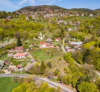 Aerial view of family houses in Štiavnické Bane surrounded by lush greenery and hills.