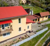 A family house in Štiavnické Bane with a red roof, a landscaped garden, and a parking space.