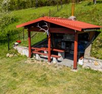 A garden gazebo by a family house in Štiavnické Bane is surrounded by green grass and trees.