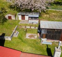 The garden of a family house in Štiavnické Bane with wooden extensions and flowering trees.