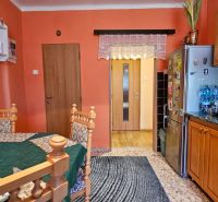 A kitchen in a family house with orange walls, wooden cabinets, and a dining table.