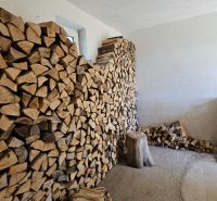 Stacked wood in the interior of a family house, next to it stands a green plastic crate.