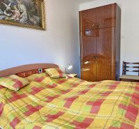Bedroom with colorful bed linens, an antique painting, and a wooden wardrobe in a family house.