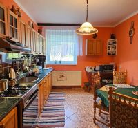 A kitchen in a family house with wooden furniture, a coffee table, and orange walls.