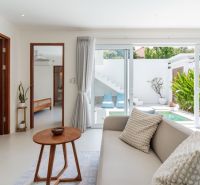 A bright living room in a villa with a view of the outdoor terrace through glass doors.