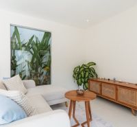 Living room in a villa with a sofa, wooden cabinet, and a plant.