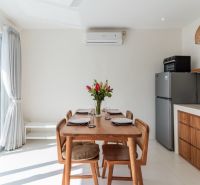 Dining room in a villa with wooden decor, kitchen unit, and dining table.
