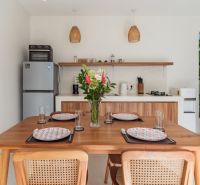 A bright kitchen in a villa with wooden decor and a dining table with flowers.