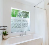 A villa bathroom with a bathtub, large window, and a potted plant.