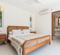 Bright bedroom in a villa with wooden furniture and a striped blanket.