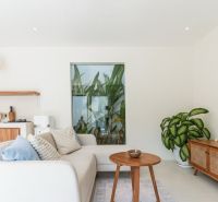 Living room in a villa with a white sofa, wooden coffee table, and a houseplant.