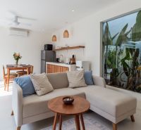 Living room in a villa with a comfortable sofa, dining table, and kitchen unit.