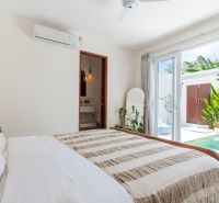 A bright bedroom in a villa with access to a terrace and a view of the pool.
