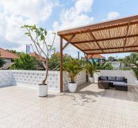 A terrace in a villa in Bali with a pergola, plants, and rattan seating.
