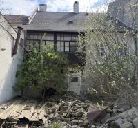 A family house in Kremnica, overgrown yard, old wooden fence, stones on the ground.