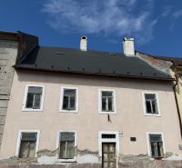 A family house in Kremnica with a worn facade and a stone plinth section.