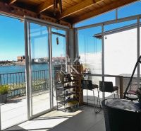 A glazed terrace with a view of the lake and seating in a family house.