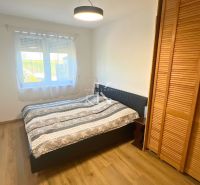 Bedroom in a family house with a bed, wardrobe, and wooden decor flooring.