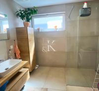 A bathroom in a family house with a bathtub, a sink, and a cabinet with a wood decor.