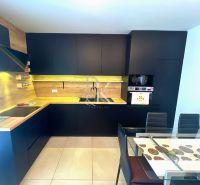 A kitchen in a family house with black furniture and a wooden decor floor.