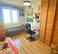 A room in a family house with one bed, a desk, and a floor with a wooden decor.