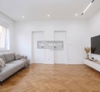Living room in a 3-room apartment with a wood-patterned floor and a TV on the wall.