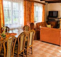 Living room of a family house with a fireplace, orange curtains, and comfortable leather seating.
