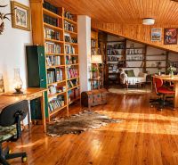 Interior of a family house with a wooden decor floor, bookshelves, and historical decorations.