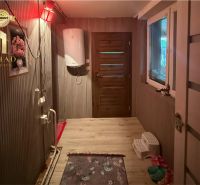 A hallway in a family house with a wooden decor floor, doors, and a water heater.