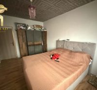 Bedroom in a family house with a bed, wardrobe, and wooden decor flooring.